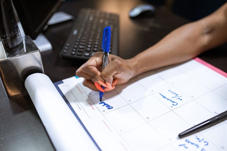 Hand writing notes on a calendar with a blue marker