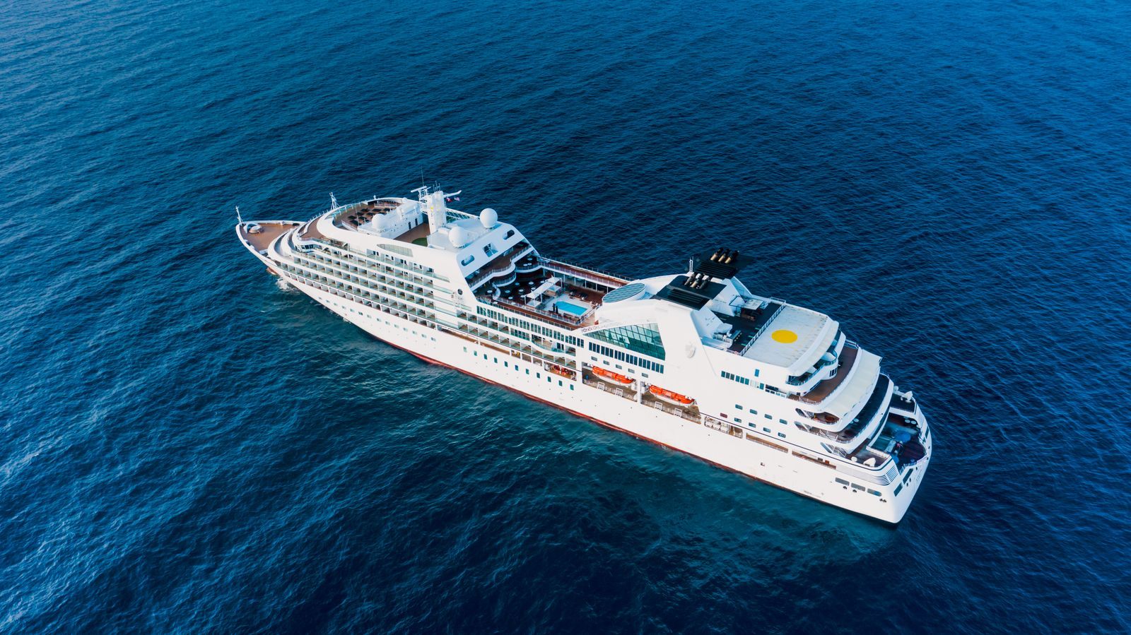 Drone view of a cruise ship on rippling blue ocean, one of thousands of cruise sailings each year