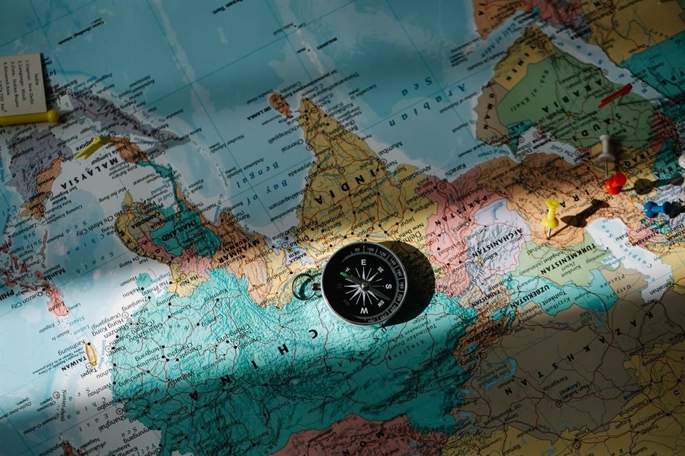 Compass on a world map with colored push pins